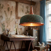 Vintage-style copper pendant light hanging in a room with a desk and window.